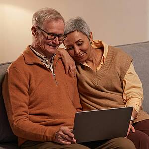Zwei ältere Personen, die in ein Laptop schauen